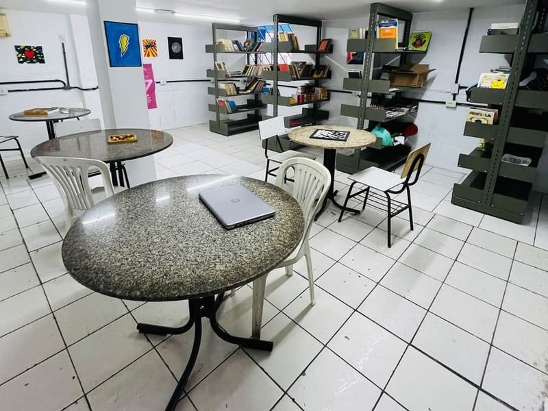 Biblioteca, com as estantes de livros e as mesas redondas de leitura