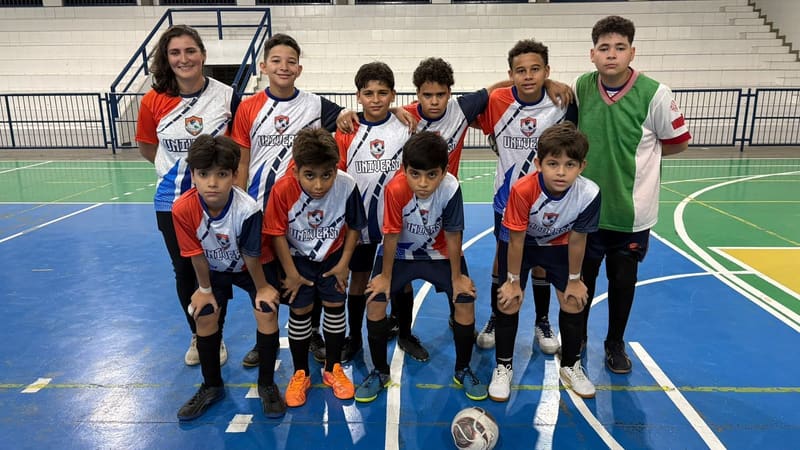 Time de futsal do colégio posado na quadra, com o uniforme de jogo