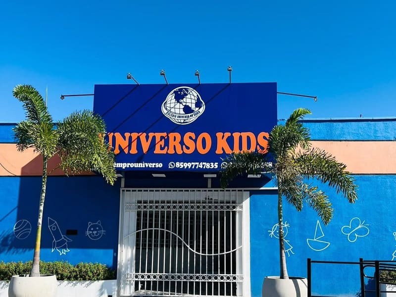 Fachada azul do Universo Kids, com o letreiro e o logo do colégio