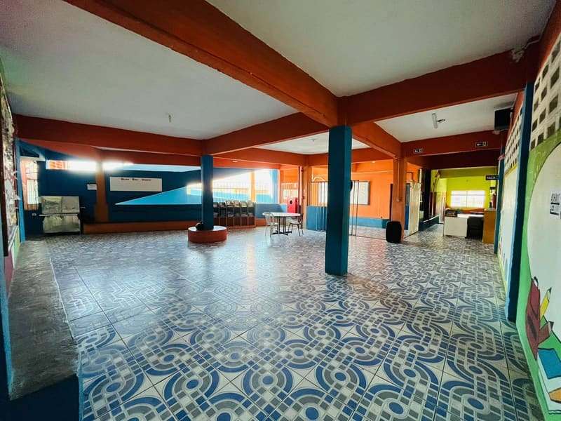 Pátio coberto, com o piso de ladrilho azul e as vigas laranja