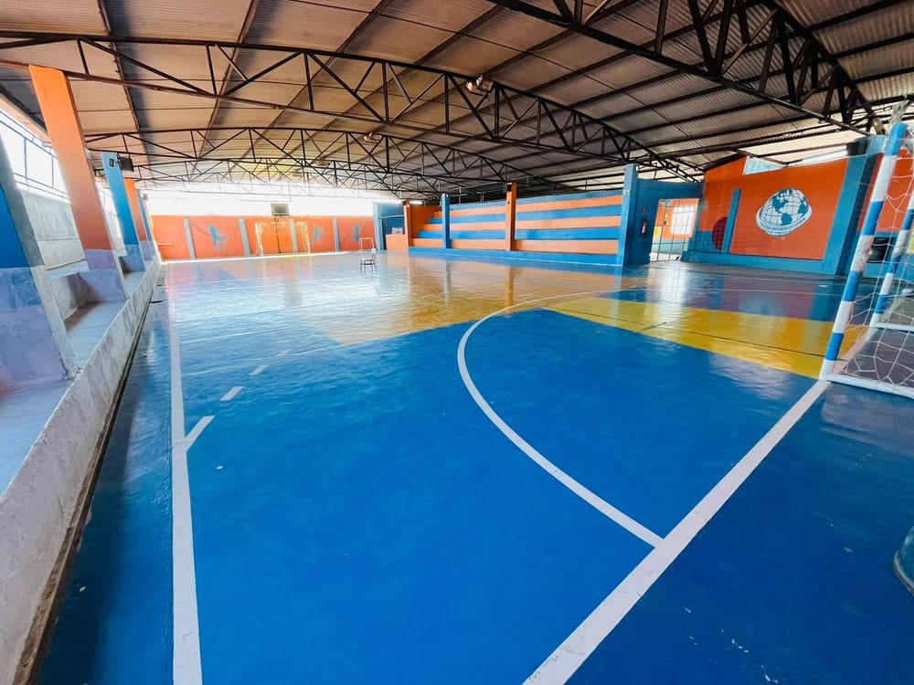 Quadra coberta, com o piso azul e as paredes laranja do colégio
