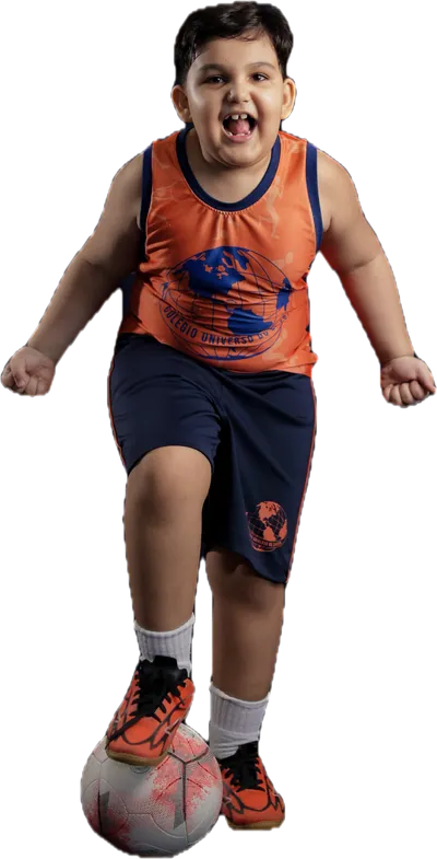 Aluno do Fundamental I com o pé na bola, de regata esportiva